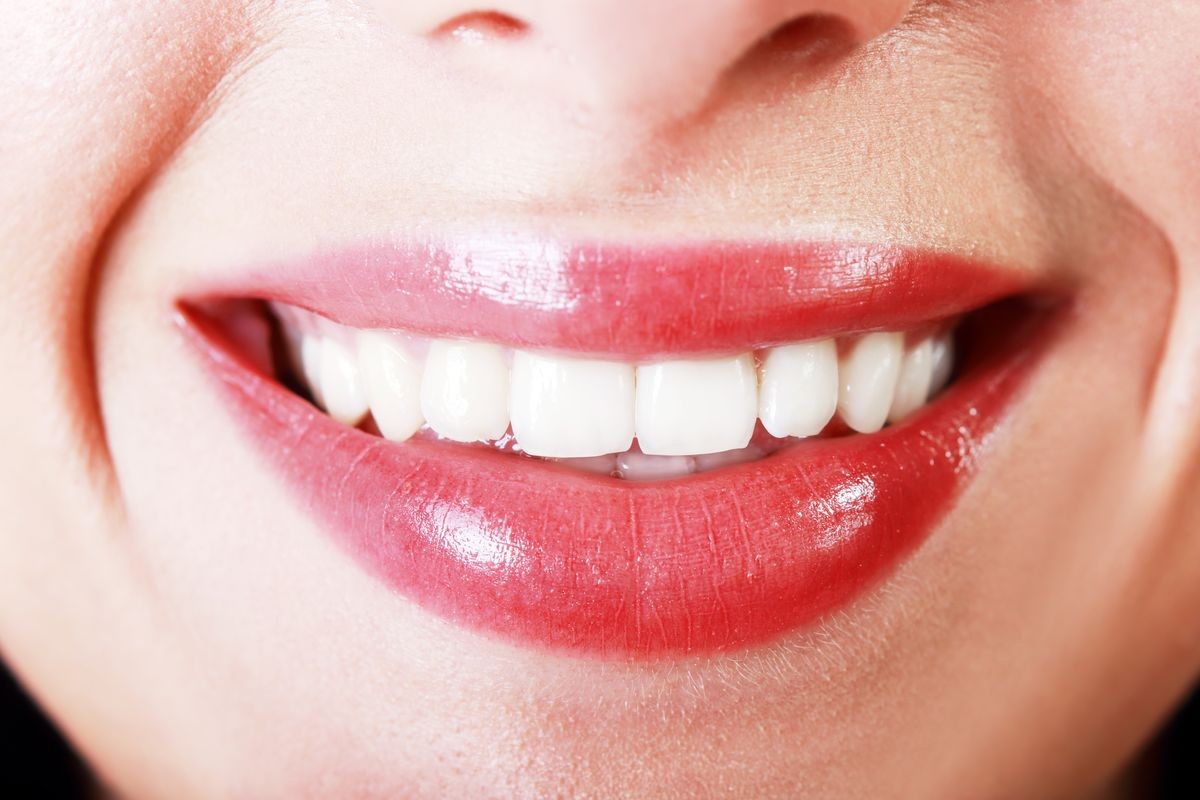 Close-up happy female smile with healthy white teeth, bright gloss lips make-up. Cosmetology, dental and beauty care 
